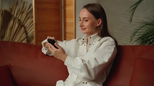 Woman Relaxing Indoors Using Smartphone on Sofa