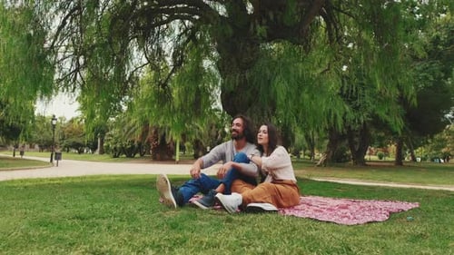 Couple talking while sitting on blanket at picnic in the park