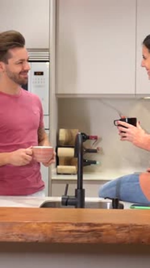 Couple Chatting in Modern Kitchen with Hot Drinks