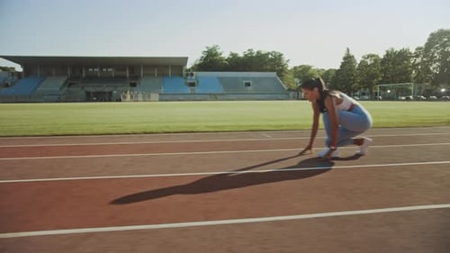 Beautiful Fitness Woman in Light Blue Athletic Top and Leggings is Starting a Sprint Run in an Outd