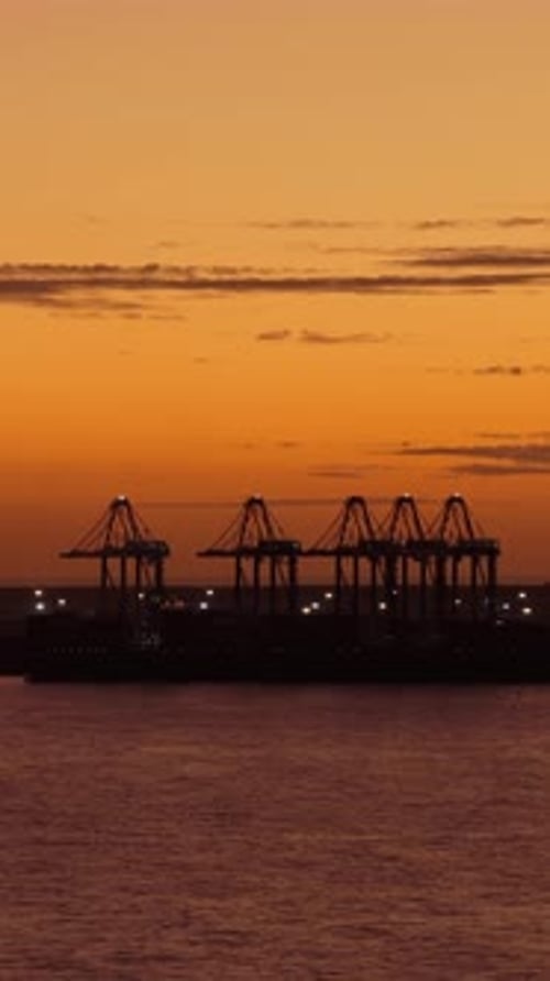 Silhouette Of Caucedo Port Cranes Against An Orange Sunset Sky, Dominican Republic. Vertical