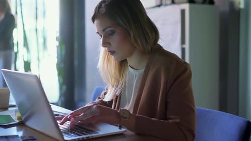 Woman Typing on Laptop in an Office