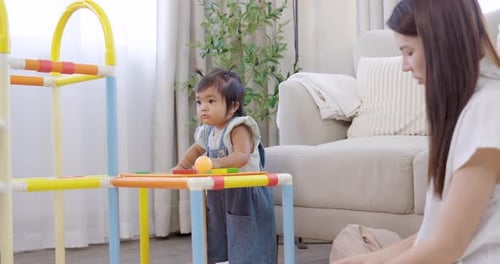 Woman playing with infant near colorful play structure
