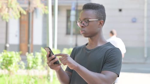 Young Adult Using Smartphone Outdoors in Urban Setting