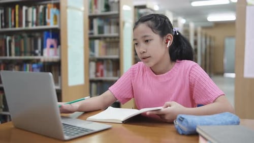 Girl Studies Online in Library with Laptop