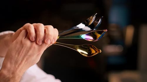 Dynamic Close-Up of Hand Holding Modern Iridescent Spoons
