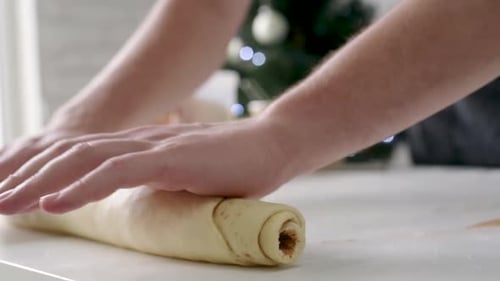 Chef making cinnamon rolls, christmas tree with lights on the background