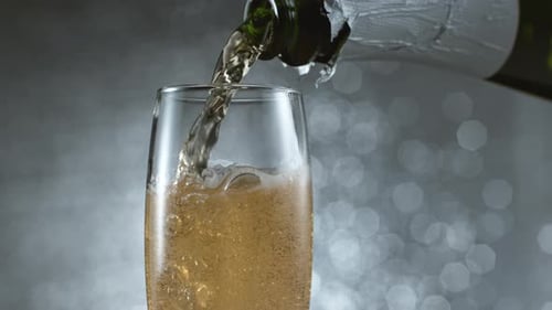 Pouring sparkling champagne into a glass on gray