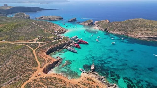 Vue par drone du Blue Lagoon de Comino avec des eaux claires, des côtes rocheuses et des bateaux ancrés