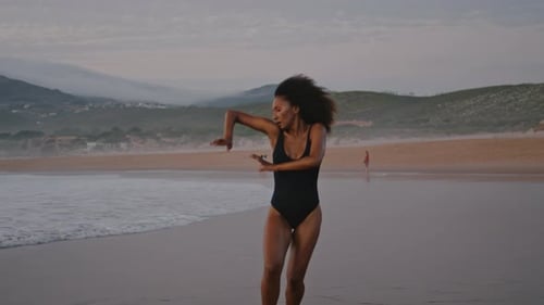 Sensual African American Woman Dancing Modern Style on Overcast Beach Wearing Black