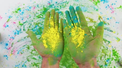 Hands Rubbing Yellow Paint Powder Together