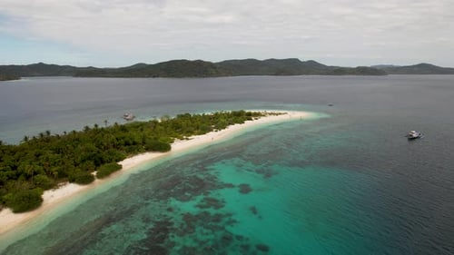 4K drone video flying towards a couple walking on a beautiful white sand beach on a tropical island