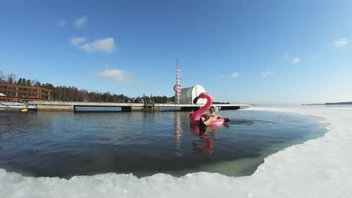 Woman Floats on Pink Flamingo in Winter Lake