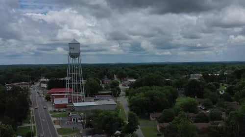 Drone flyover of a small town towards a water tower.