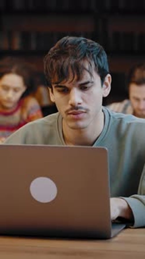 Young Man Student Prepare for Examinations at Library Using Laptop