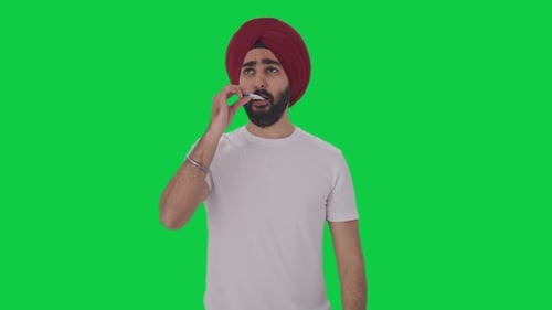 Sick Sikh Indian man using thermometer to check fever Green screen