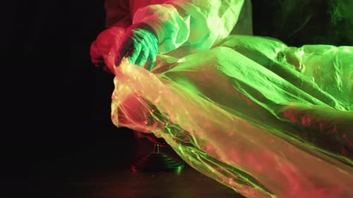 Person Covering Globe in Plastic Sheet with Dark Lighting