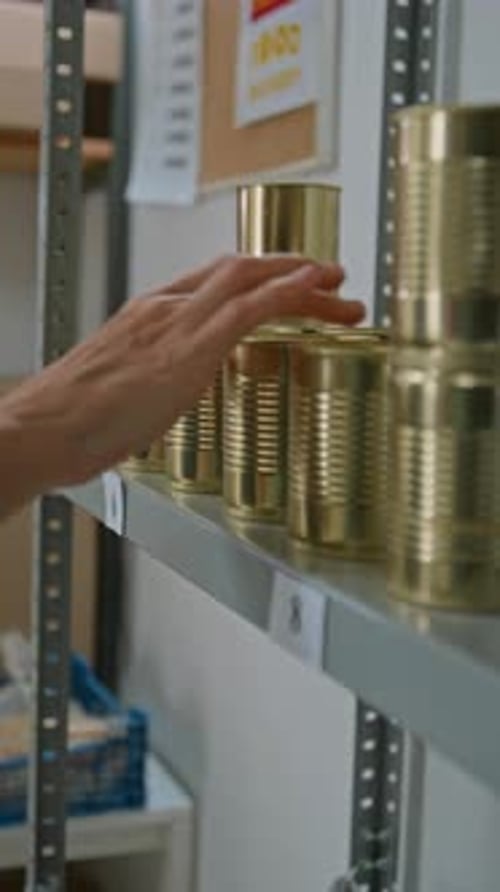 Hands of Female Employee Picking Up Canned Preserves from Shelf at Dark Store