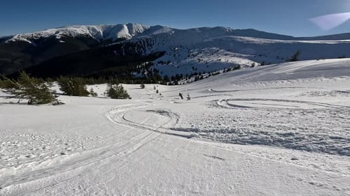 Skiers Descend Snowy Mountain Slopes on Sunny Day
