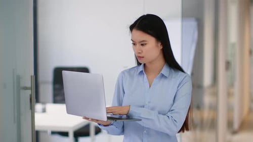 Young Asian Woman Working on a Laptop in an Office Environment During the Day