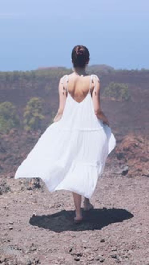 Woman Dancing Freely Woman in Flowing White Attire Dances on Rugged Volcanic Plateau Beneath Clear
