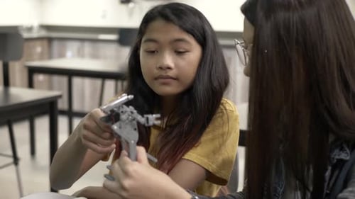 Two girls assemble robot in a classroom