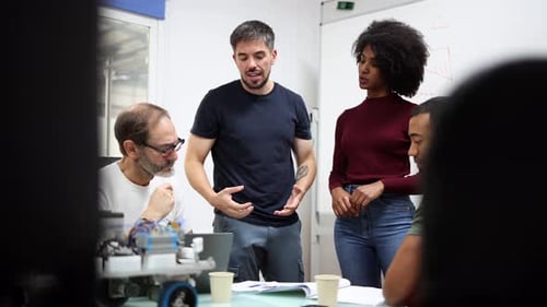 Diverse engineers collaborate on robotics project in modern factory, fostering innovation and teamwo