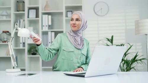 Woman employee entrepreneur. office worker Turn on a remote control air conditioner, cooling system