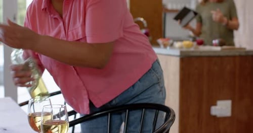 Sosteniendo una copa de vino, mujer en camisa rosa disfrutando del tiempo en casa