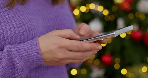 Person Using Smartphone Near Christmas Tree