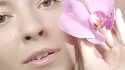 The Face of a Young Woman with Clean Skin in the Studio on a Pink Background Close Up A Woman