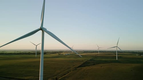 Wide Drone View of a Wind Park with Wind Turbines Standing in a Wheat Field at Sunset