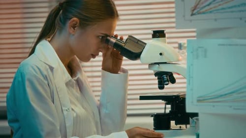 Woman in Lab Coat Using Microscope in Laboratory
