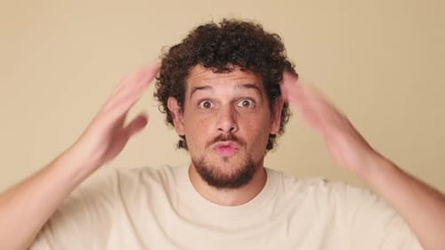 Close up, surprised man looking at the camera with big eyes, says wow, on beige background