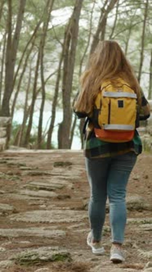 Vertical video. The camera follows a woman on a journey or adventure along the overgrown main street