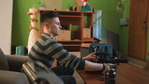 Person Seated in Home Studio Assembling Camera Equipment