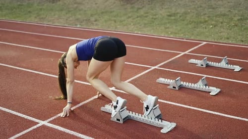 Female Athlete Sprinting from Starting Block on Track