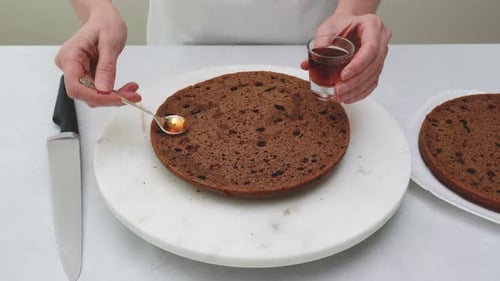 Chef Spreading Liquid on Chocolate Cake Layer