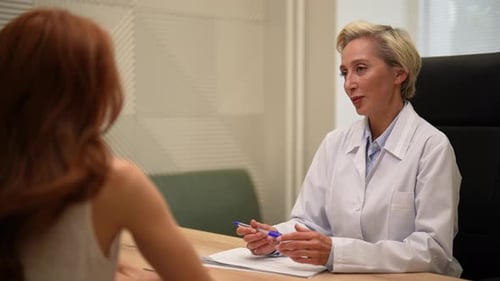 View From Shoulder of Unrecognizable Young Woman Patient to Friendly Middleaged Female Doctor