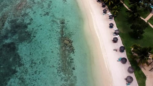 Aerial birds eye shot of sandy beach,relaxing people with umbrella in paradise