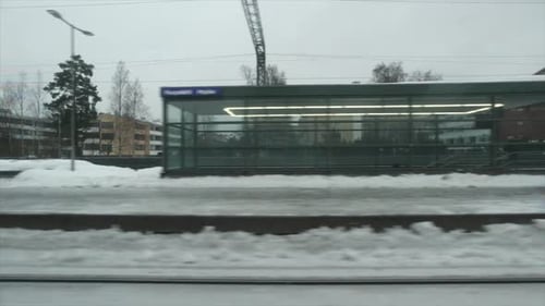 Winter city train pulls into snowy station platform on cold grey day