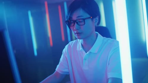 Young Man Works At Computer Station With Neon Lights