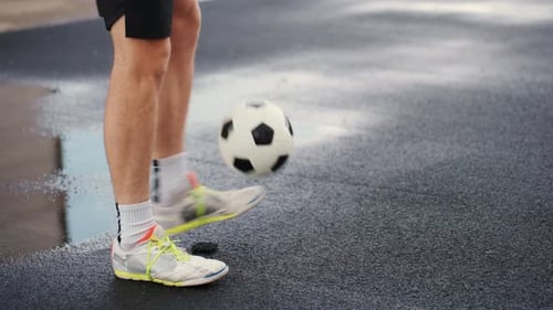 Man Juggling Soccer Ball with Feet on Asphalt Surface