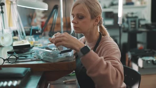 Woman Jeweler Crafting Jewelry at Workbench in Workshop