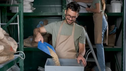 Male brewer grinding barley in brewery warehouse.