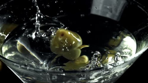 Olives Dropping into Clear Martini Glass
