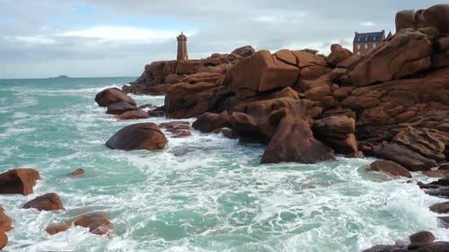 Scenic Coastal View Of Stone Lighthouse And Rugged Brown Rocks
