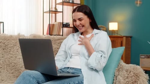 Cheerful Woman Using Laptop on Sofa at Home
