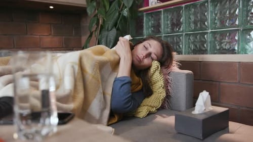 Woman lying on couch with a cold