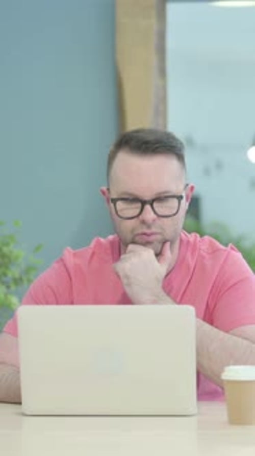Man Working on Laptop at Desk With Coffee